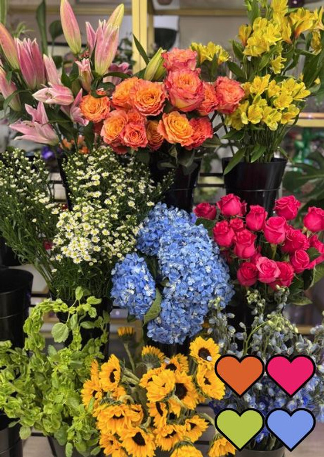 A vibrant selection of fresh flowers, including sunflowers, roses, lilies, and hydrangeas, ready for a custom bouquet by our designer.